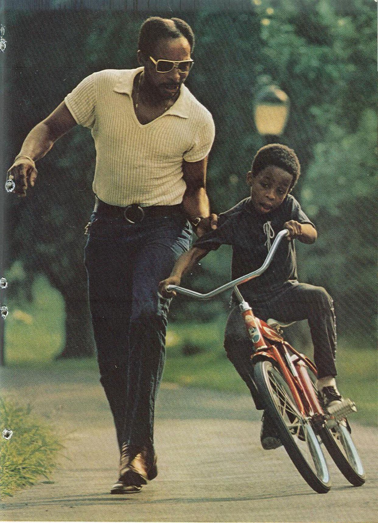 Father holding onto his son's arm as he learns how to ride a bike