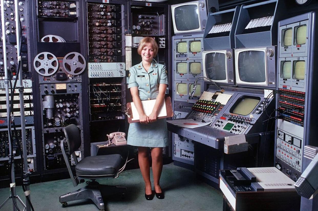 A woman in an Army uniform in front of televisions