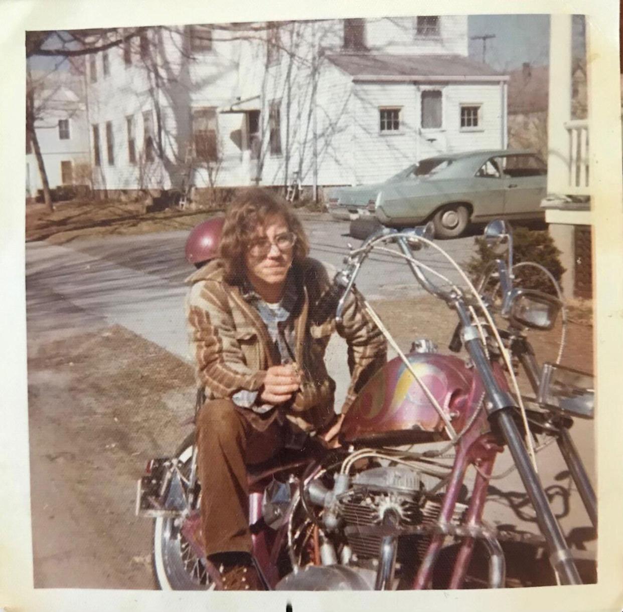 A young man sitting on a pink motorcycle