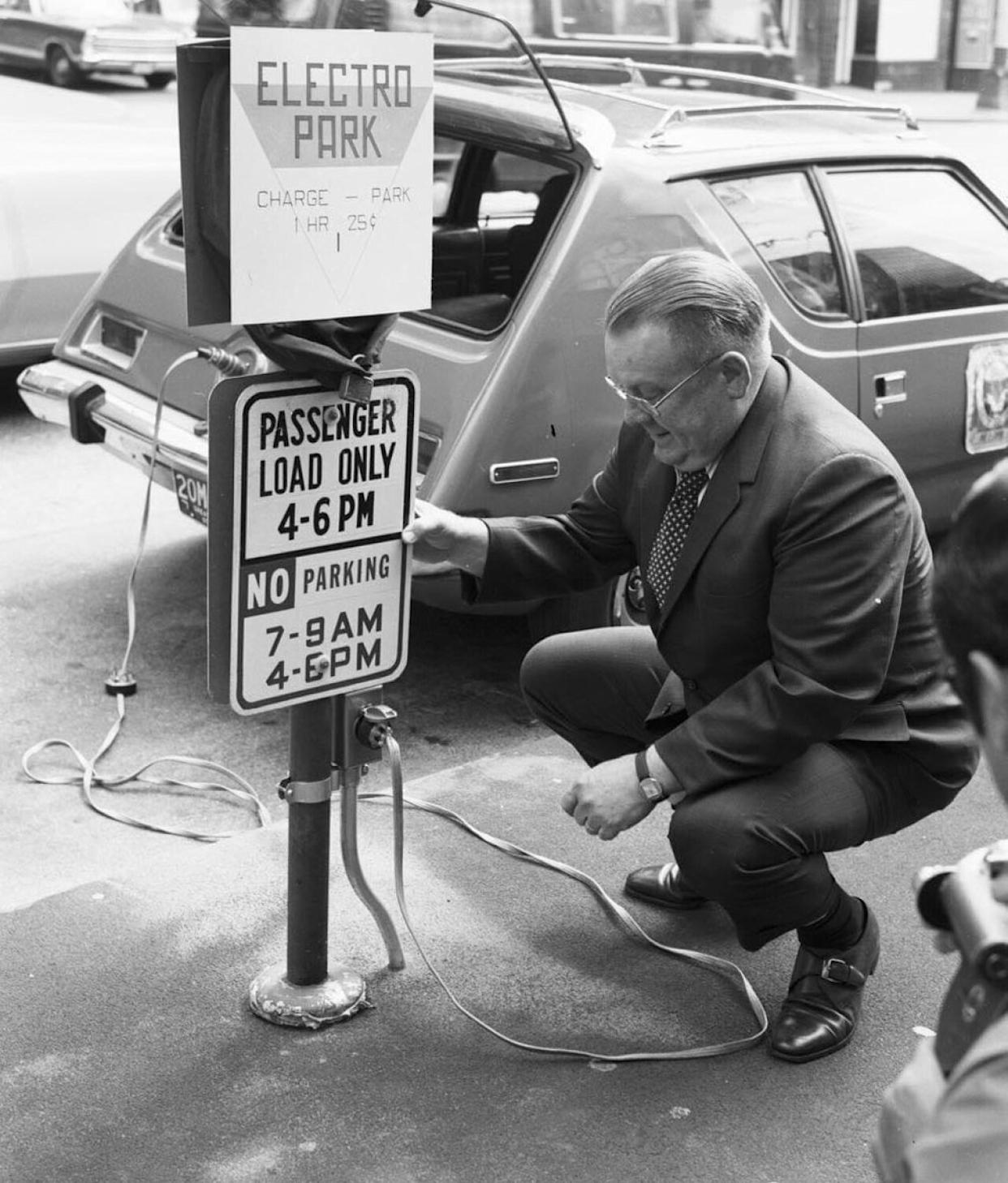 A man charging an electric car in the 1970s