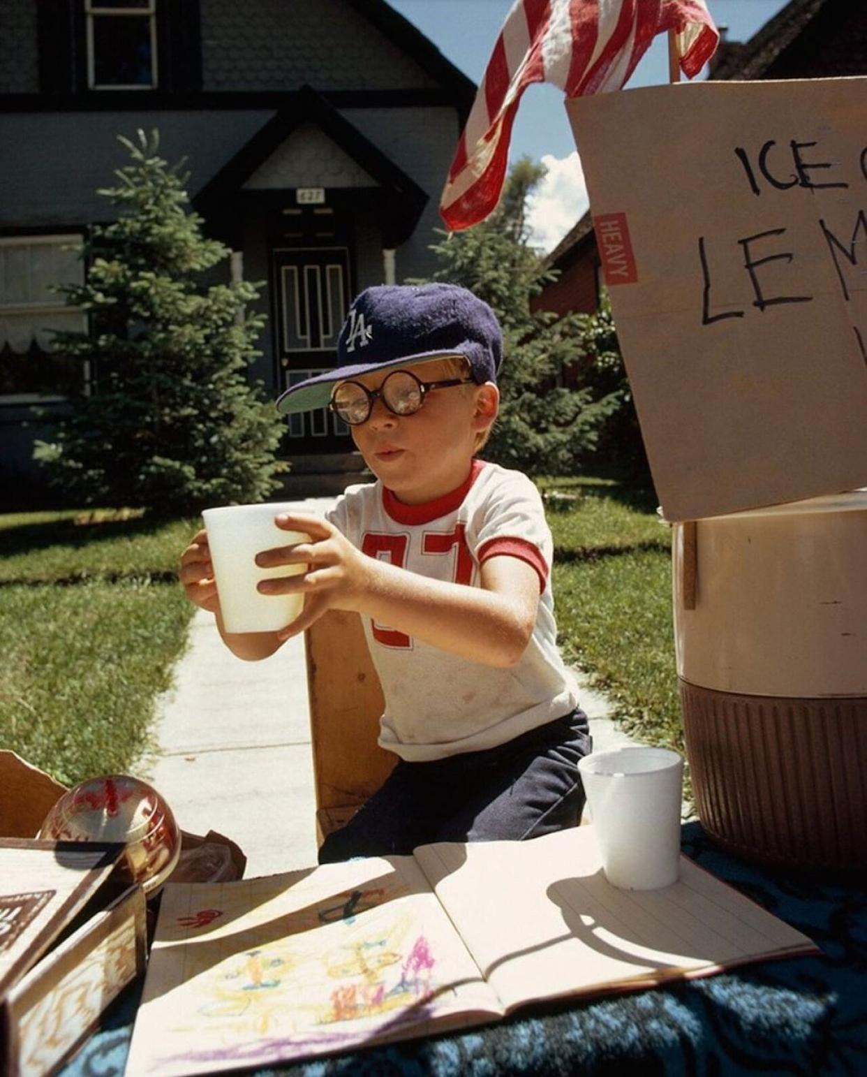 A boy wearing a Dodgers ball cap selling lemonade