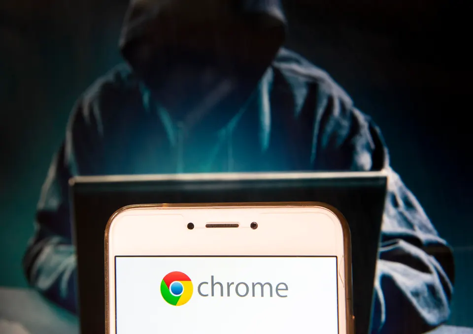 Chrome logo on laptop, hooded figure behind.