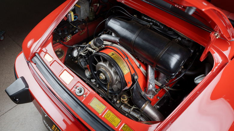 A red air-cooled Porsche 911 with an open engine bay